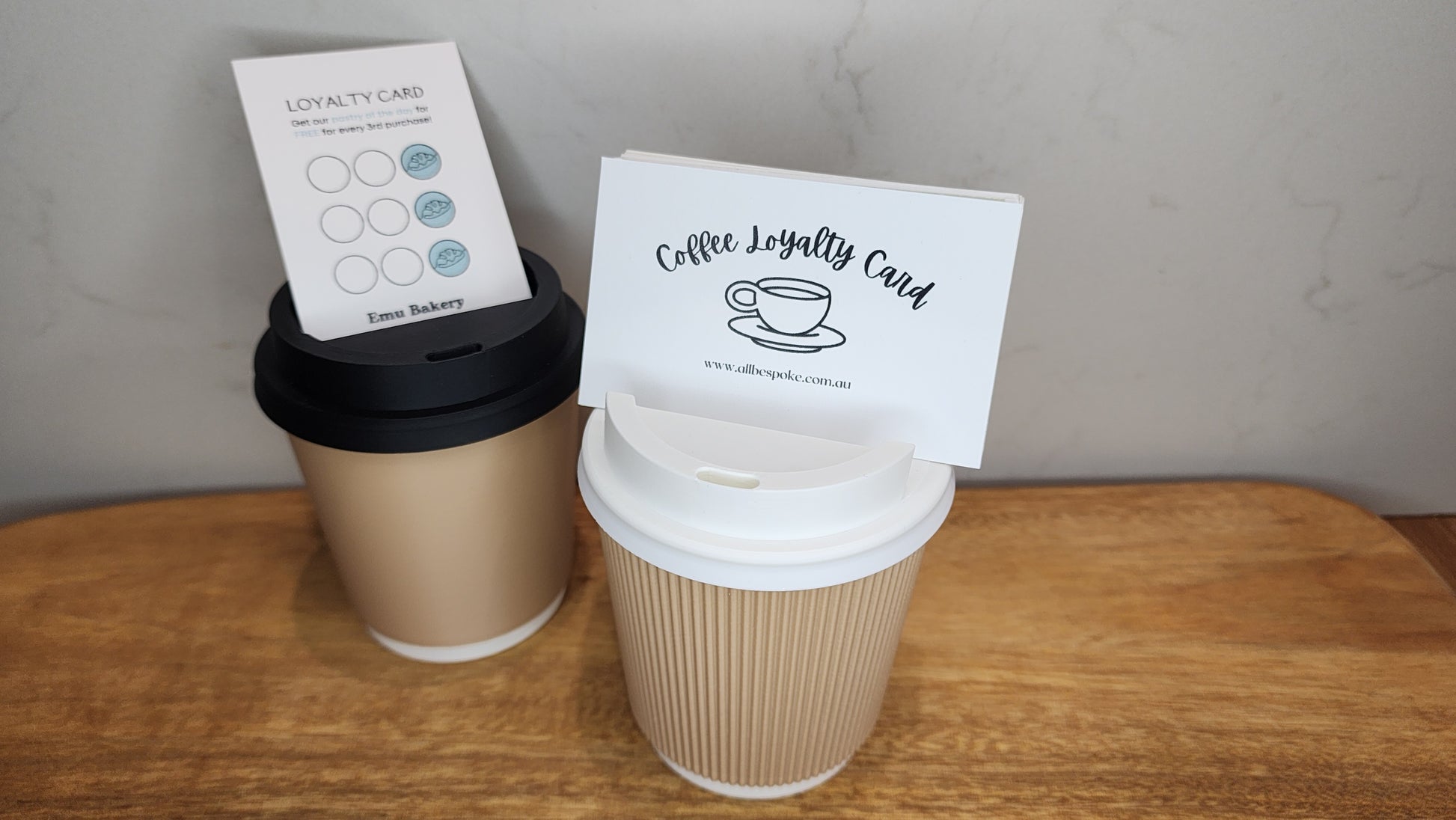 Two coffee cups with loyalty cards on a wooden surface